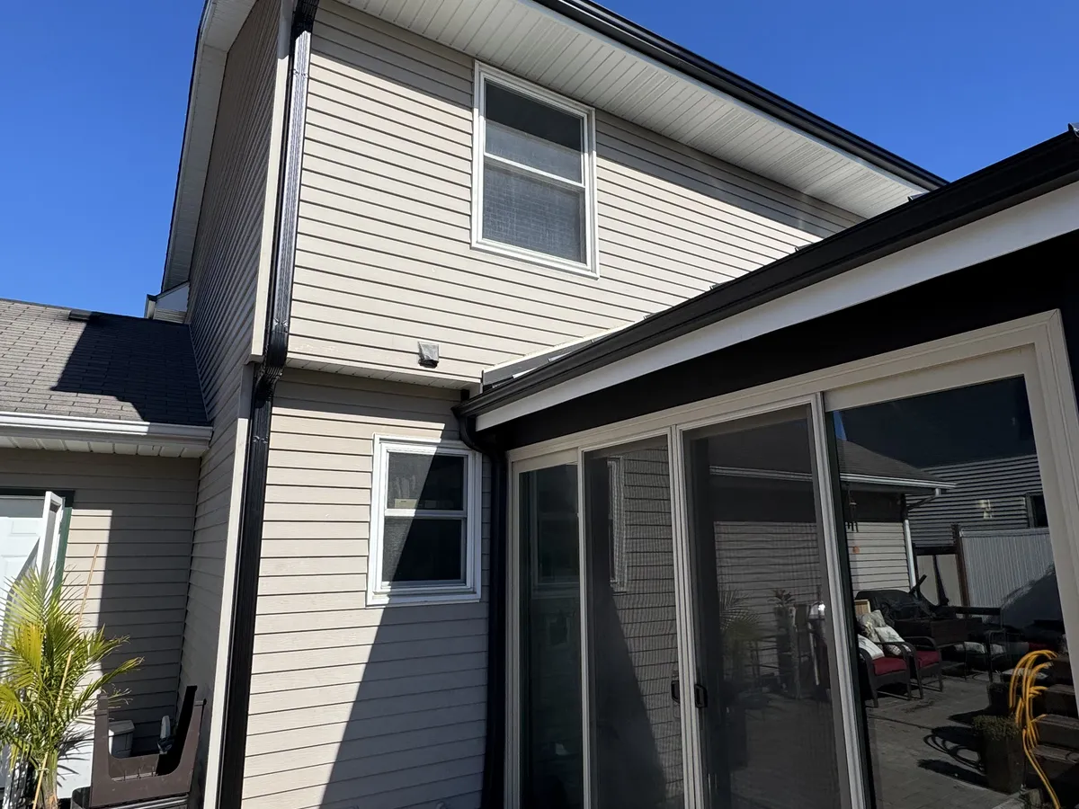 Black seamless gutters installed around a covered residential patio