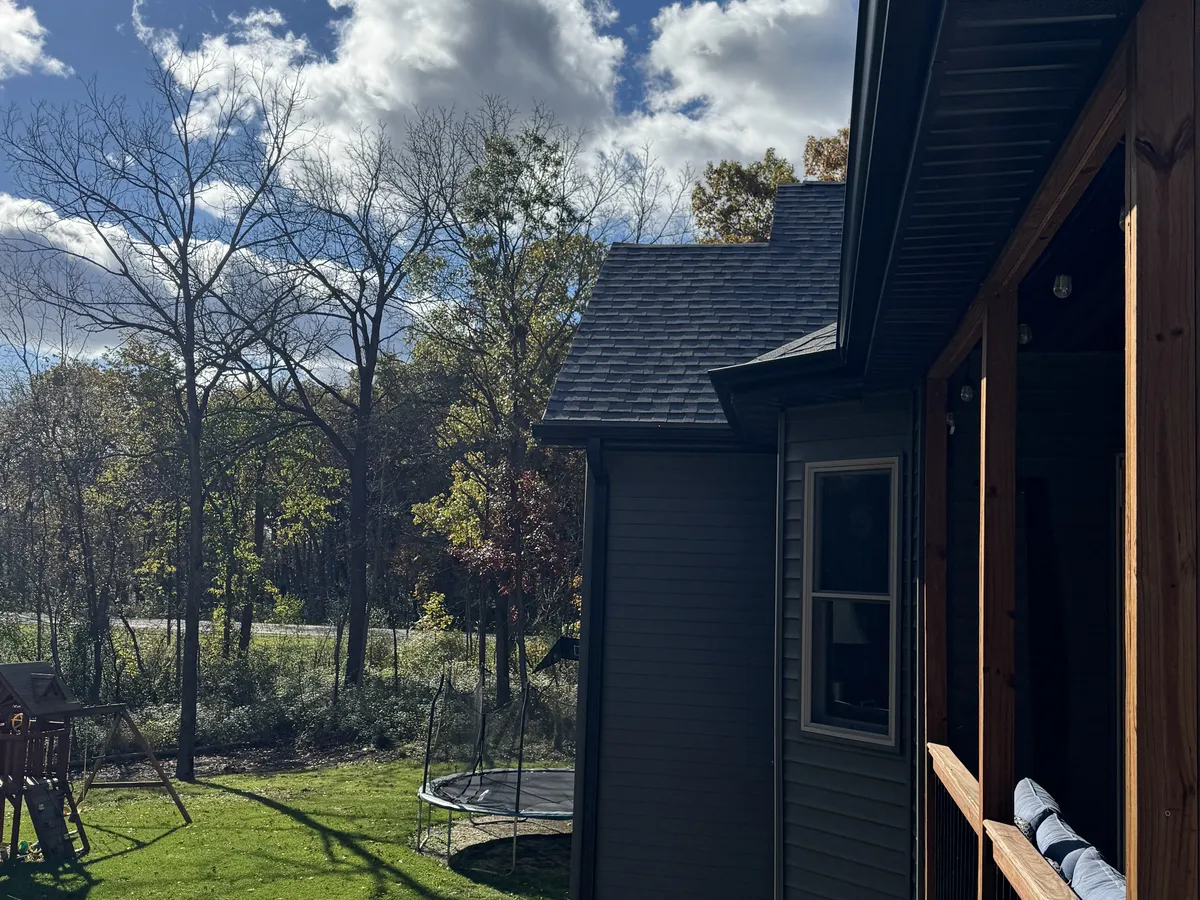 Black seamless gutters installed along the side roofline of a home