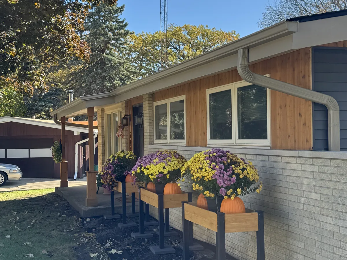 Seamless gutters installed above a front porch decorated with flower boxes