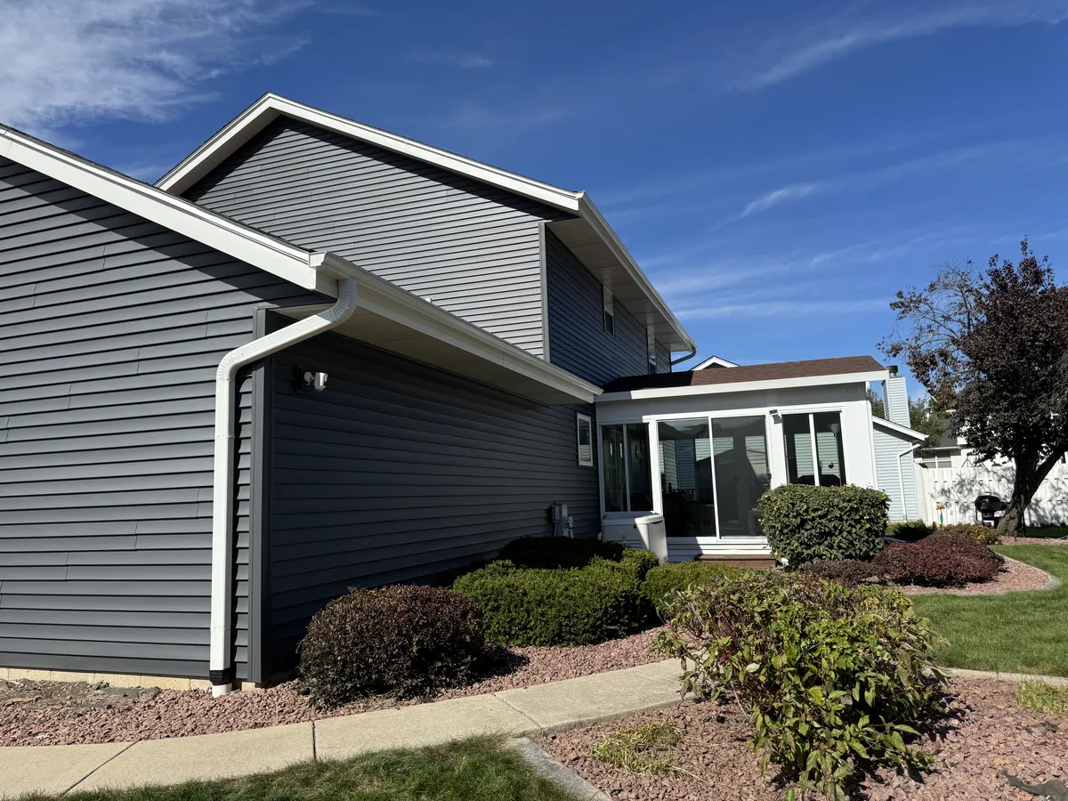 White seamless gutters and downspout installed on a gray garage