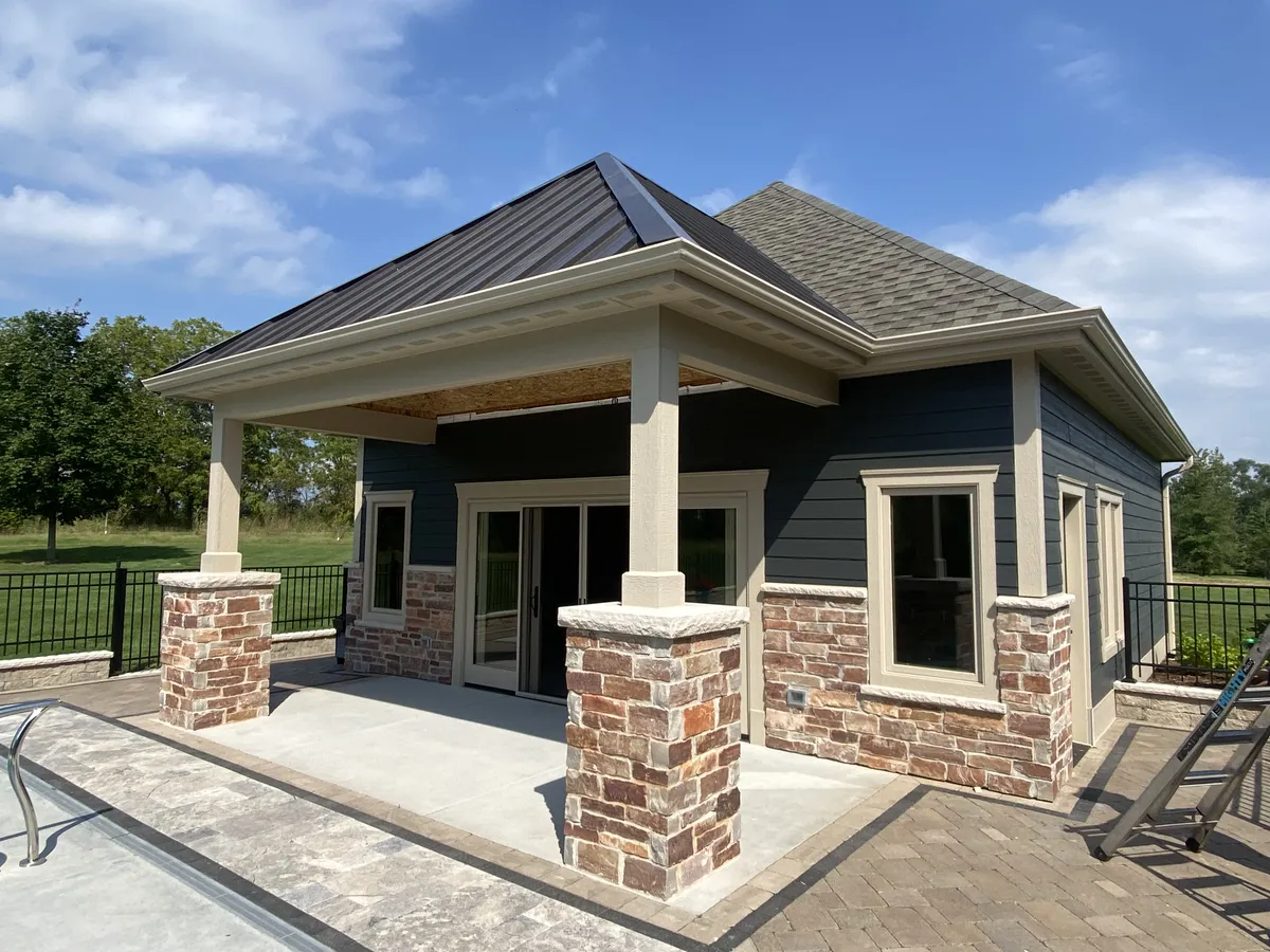 White gutters and downspout installed above a patio on a gray home