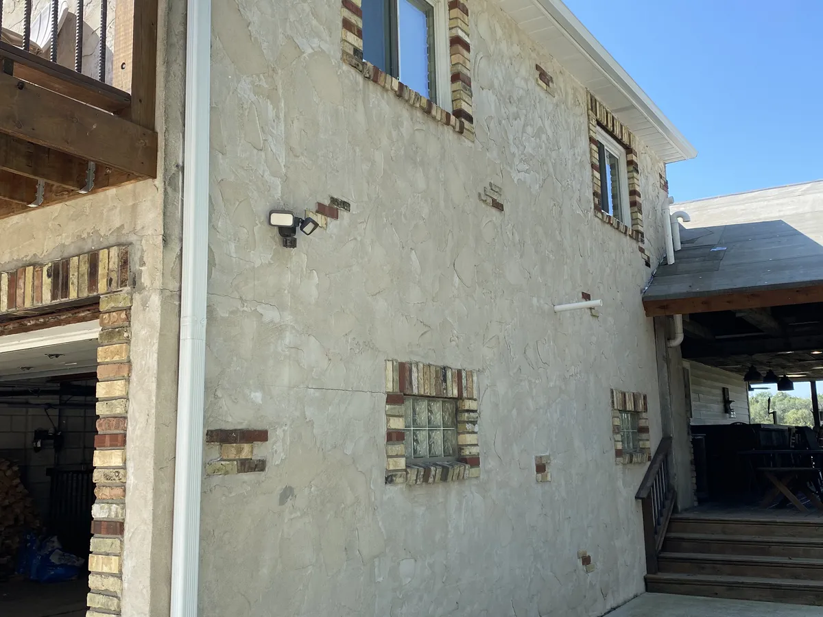 White seamless gutters installed along the roofline of a stone home