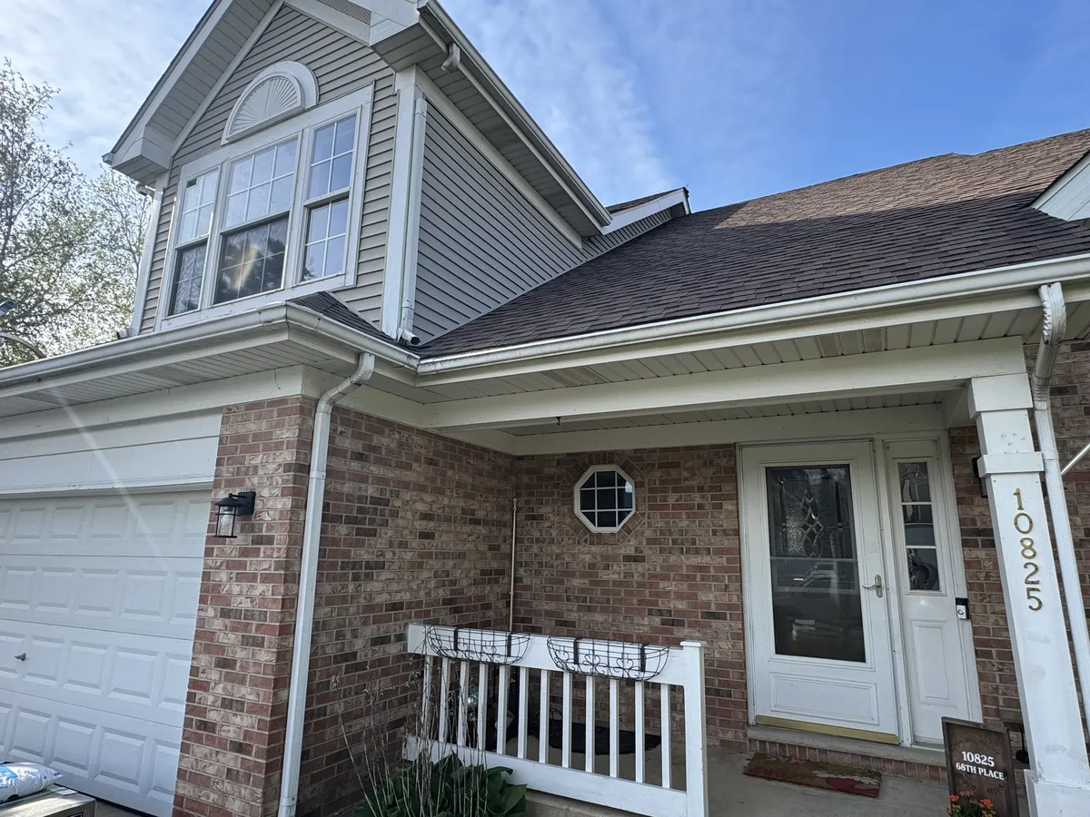 White seamless gutters installed above a brick home's front entry