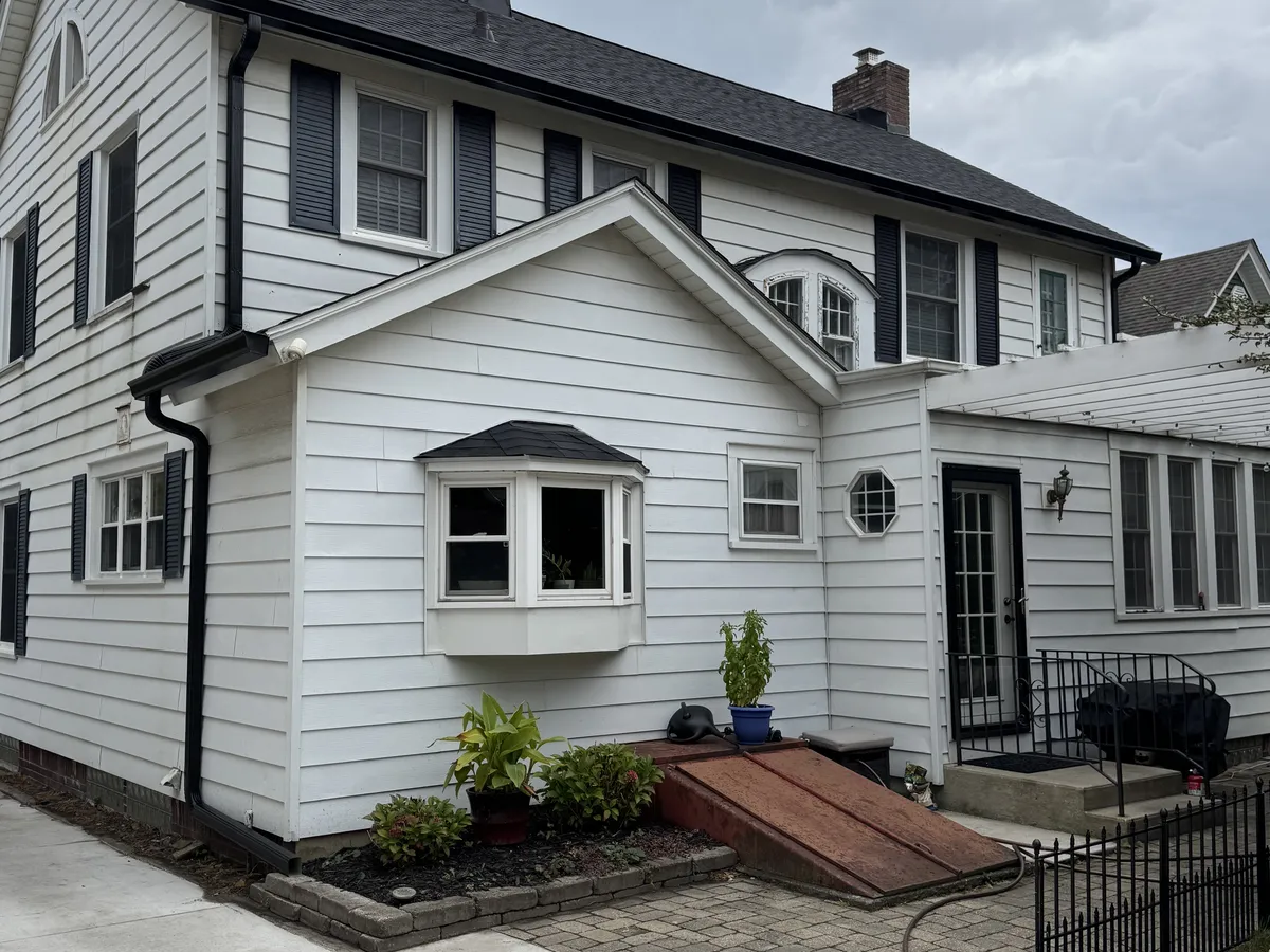 White seamless gutters installed on a white colonial-style home