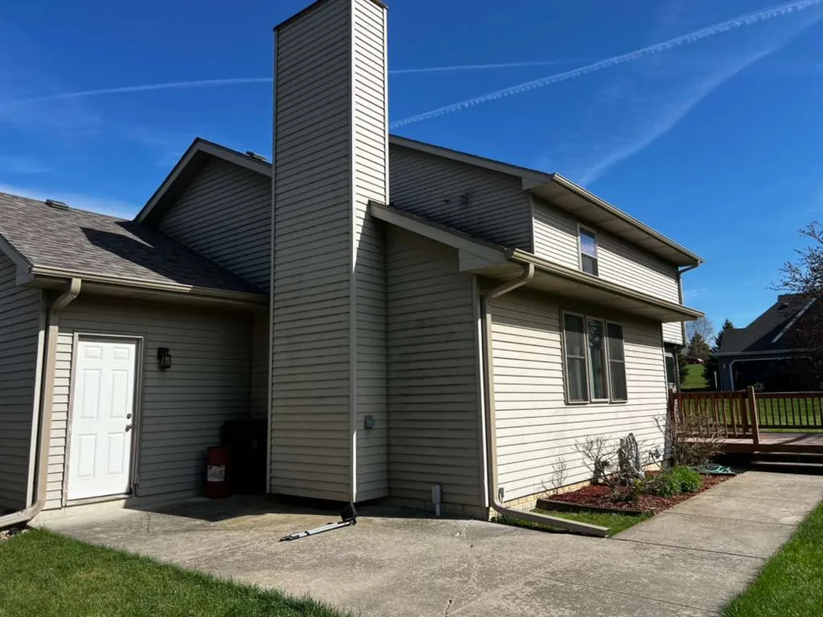 White seamless gutters installed on a gray home with a tall chimney