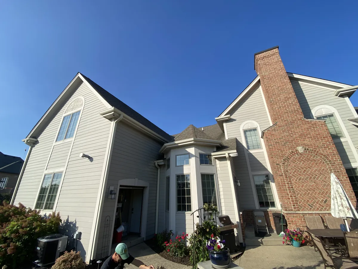 White gutters and downspouts installed where two residential rooflines meet