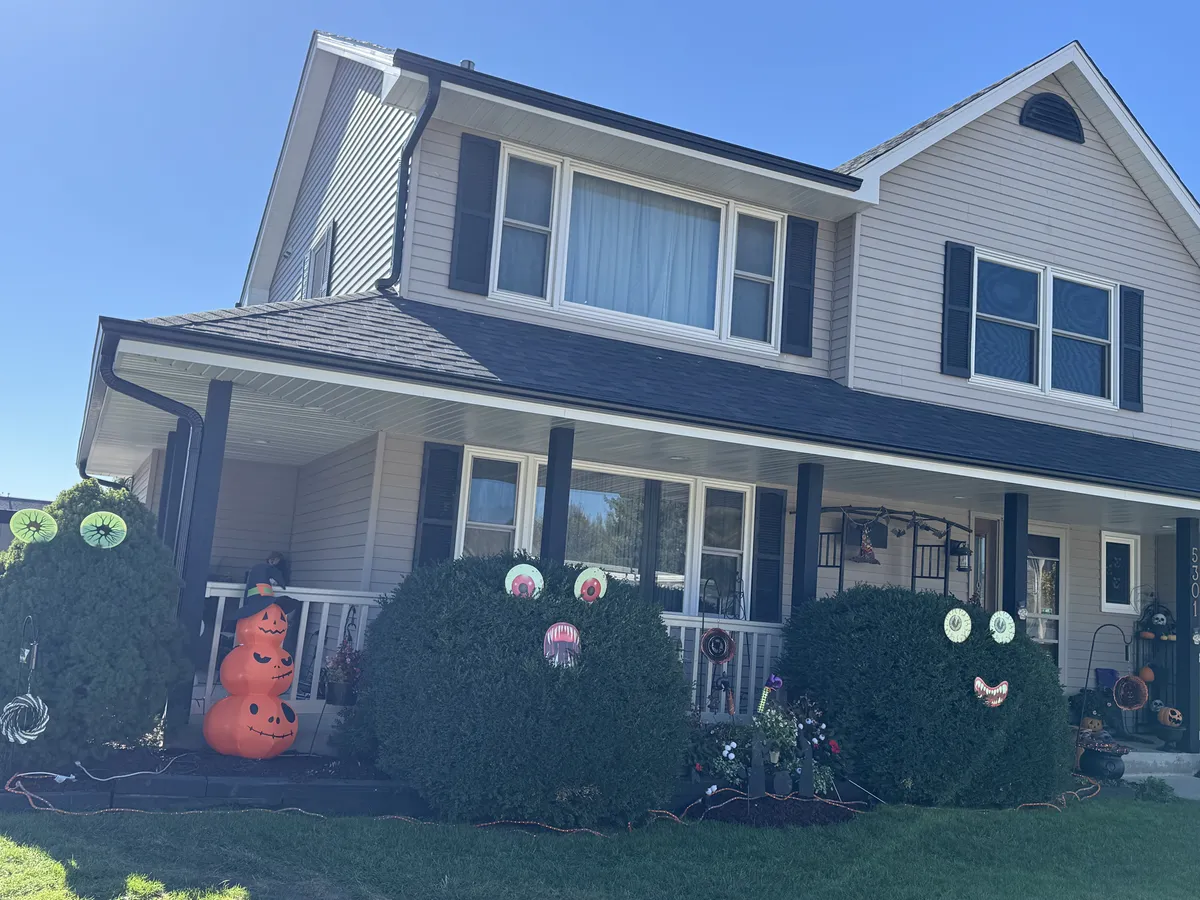 White seamless gutters installed above a suburban home's front porch