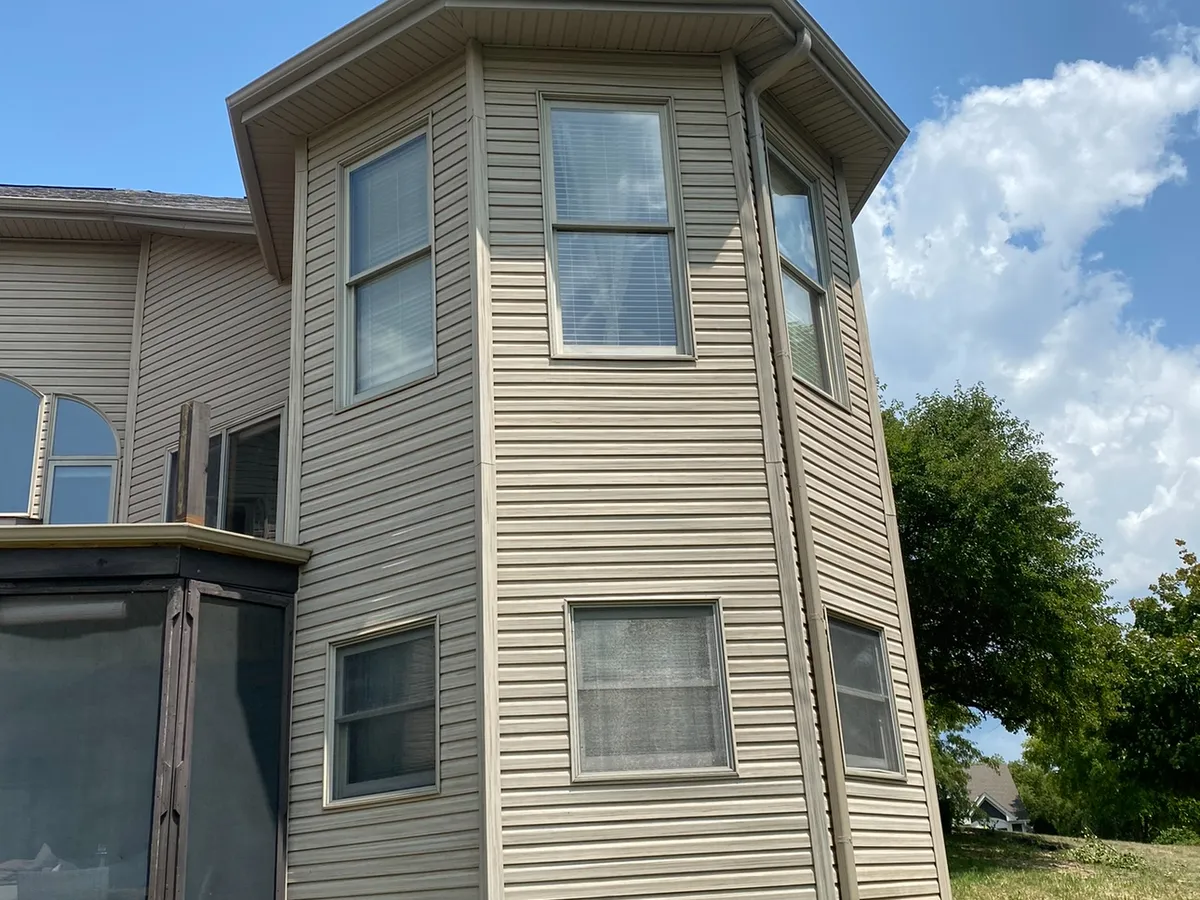 White seamless gutters installed around a two-story bay-style home